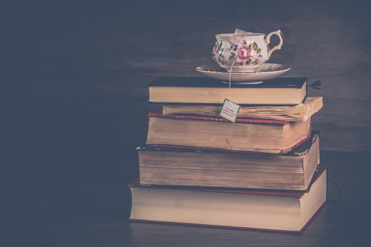 Beyaz bir çay fincanı, en üstteki açık olmak üzere bir yığın kitabın üzerinde durmaktadır. Çay fincanı kırmızı bir ip ve bir çay poşeti ile süslenmiş, çay poşetinin etiketi yakından görülebiliyor. Kitapların arkasında bir parça kek ve resmin köşesinde küçük bir çiçek görülebiliyor. Kitaplar koyudan açığa çeşitli renklere sahip ve bazılarının sırtlarında başlıklar var. Parlak beyaz rengi ve kitap yığınının üzerindeki mükemmel dengesiyle çay fincanı resmin odak noktası.