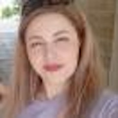 Bu, uzun siyah saçlı genç bir kadının fotoğrafı. Doğrudan kameraya bakarken yüzünde ciddi bir ifade var. Saçları geriye çekilmiş ve yüzünden uzakta, sırtından aşağıya, omuzlarını geçecek şekilde sarkıyor. Gözleri koyu renk ve delici; kaşları konsantrasyonla hafifçe çatılmış. Dolgun, belirgin dudakları ve güçlü bir çene hattı var. Cildi pürüzsüz ve berraktır ve yüzünde hafif, ışıltılı bir parlaklık vardır. Uzun kollu, sade siyah bir bluz giyiyor ve duruşu güçlü ve kendinden emin. Önüne çıkan her türlü zorluğu üstlenmeye hazır görünüyor.