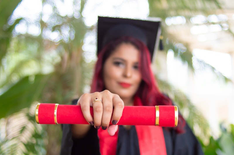 Mezuniyet cübbesi giymiş gülümseyen bir kadın, bir elinde gururla diplomasını tutuyor. Uzun, kızıl saçları var ve sarı bir püskülle süslenmiş siyah bir kep takıyor. Diğer elinde altın bir yüzük tutmaktadır ve yüzü hafifçe bulanıktır ancak sevinç ve başarı ifadesi görülebilmektedir. Büyük bir kalabalığın önünde bir sahnede durmaktadır ve güneşin ışığı üzerine vurmaktadır. Bu an önemli bir yolculuğun sonunu ve yeni bir yolculuğun başlangıcını işaret ediyor.