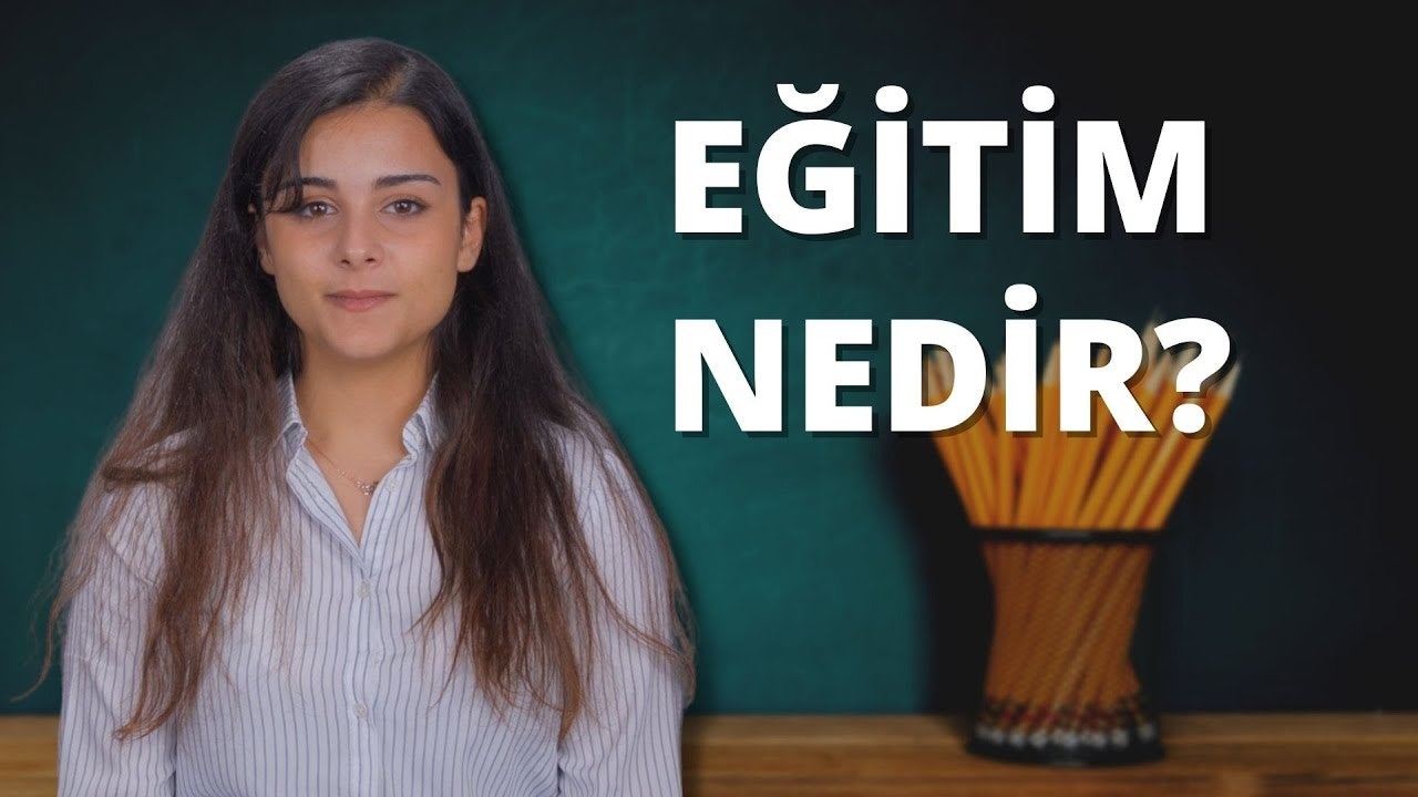 Beyaz bir tişört ve siyah kot pantolon giyen bir kadın kara tahtanın önünde duruyor. Uzun saçları gevşek bir at kuyruğu şeklinde geriye doğru toplanmıştır. Sağ elinde birkaç kalem, sol elinde ise içinde daha fazla kalem bulunan siyah bir tutacak tutmaktadır. Boynuna yakından bakıldığında narin bir kolye görülüyor. Arka plan canlı bir yeşil ve kara tahtanın üzerinde beyaz harflerle yazılmış bir tabelanın yakın çekimi var. Kara tahtanın önünde duran kadının kendine güvenen bir havası var. Bakışları kelimelere odaklanmış, sanki onları dikkatle inceliyor. Görüntü bir bilgi ve anlayış hissi uyandırıyor.