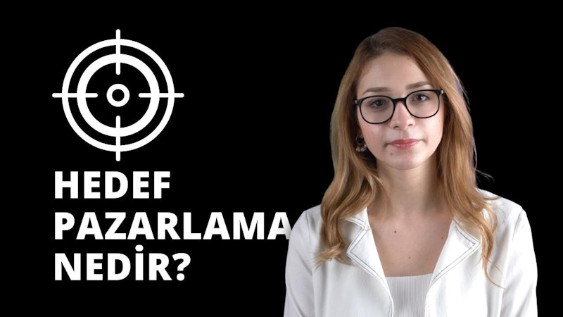 Beyaz gömlek giymiş gözlüklü bir kadın dosdoğru karşıya bakıyor. Açık tenli, gözleri kapalı ve dudakları hafifçe ayrık. Saçları kahverengi ve yüzünden geriye doğru toplanmış. Bir çift yuvarlak, siyah çerçeveli gözlük takıyor. Gömleği beyazdır ve iki düğmeli bir yakası vardır. Kolları iki yanında ve elleri kucağında duruyor. Yüzünde ciddi bir ifade vardır. Gözleri gözlükleriyle çerçevelenmiş ve kaşları hafifçe çatılmış. Burnu düz ve çenesi hafif sivri.