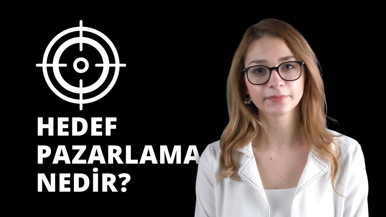 Beyaz gömlek giymiş gözlüklü bir kadın dosdoğru karşıya bakıyor. Açık tenli, gözleri kapalı ve dudakları hafifçe ayrık. Saçları kahverengi ve yüzünden geriye doğru toplanmış. Bir çift yuvarlak, siyah çerçeveli gözlük takıyor. Gömleği beyazdır ve iki düğmeli bir yakası vardır. Kolları iki yanında ve elleri kucağında duruyor. Yüzünde ciddi bir ifade vardır. Gözleri gözlükleriyle çerçevelenmiş ve kaşları hafifçe çatılmış. Burnu düz ve çenesi hafif sivri.