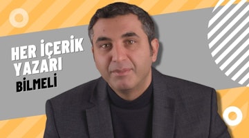 Takım elbiseli bir adam kameranın önünde durmaktadır. Adamın orta uzunlukta kahverengi saçları vardır ve siyah bir gömlek giymektedir. Yüzünde ciddi bir ifade vardır ve çenesi hafifçe kalkıktır. Dudakları hafifçe ayrıktır ve gözleri ileriye odaklanmıştır. Yakın çekimde kulakları görünür ve boynu hafifçe bükülmüştür. Adamın üzerinde tam takım bir elbise, altında beyaz bir gömlek ve siyah bir ceket vardır. Elleri birbirine kenetlenmiş ve duruşu diktir. Takım elbisesi tam oturmuş ve kendinden emin ve sakin görünüyor. Arka plan bulanıklaştırılarak odağın adamda kalması sağlanmış. Uzun boylu ve güçlü duruyor, önündeki her türlü zorluğu üstlenmeye hazır.