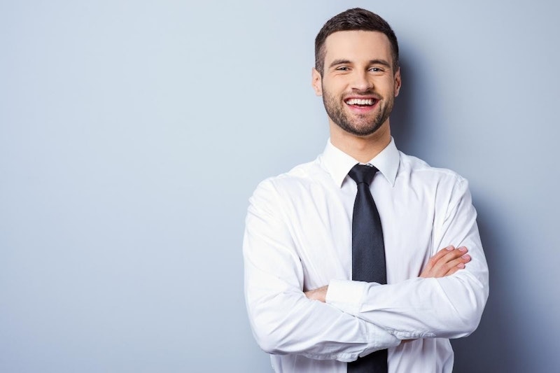 Beyaz elbise gömleği giymiş ve kravat takmış bir adam kameraya dönük durmaktadır. Gömleğin düğmeleri sonuna kadar iliklenmiş ve kravat yakanın etrafından düzgünce bağlanmıştır. Adamın kısa siyah saçları ve yüzünde ciddi bir ifade vardır. Doğrudan kameraya bakmaktadır ve gözleri odaklanmıştır. Arka plan düzdür ve başka görünür bir ayrıntı yoktur. Adam profesyonel bir işyeri ortamında görünüyor. Görüntünün odağı açıkça adam ve giysileri üzerinde ve görüntü profesyonellik ve soğukkanlılık hissi veriyor.