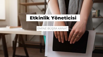 Genç bir kadın aydınlık bir odada durmuş, elindeki siyah ciltli kitaba bakmaktadır. Elleri birkaç yüzükle süslenmiş ve tırnakları kırmızının koyu bir tonuna boyanmış. Arka planda, ahşap bir masanın üzerinde bir dizüstü bilgisayar ve duvarda bir ray görülüyor. Dizüstü bilgisayar ekranında siyah beyaz bir logo ve ön planda siyah beyaz logolu bir tabela görülüyor. Kadının parmağındaki yüzüğün yakın çekimi de görülebiliyor. Kadın kitap okuyor gibi görünüyor, yüz ifadesi düşünceli ve odaklanmış.