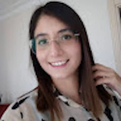 Bu, dişlerini göstererek gülümseyen gözlüklü genç bir kadının görüntüsüdür. Omuzlarına dökülen koyu renk saçları var ve ince metal çerçeveli gözlükler takıyor. Gözleri parlak ve yanakları pembe. Mavi bir gömlek giyiyor ve yüzünde memnuniyetini ve mutluluğunu gösteren sıcak bir gülümseme var. Burnu hafifçe kalkıktır ve dudakları gülümseme şeklinde kıvrılmıştır. Çenesi hafifçe sivri ve başı hafifçe yana eğik, bu da ona yaramaz bir görünüm veriyor. Harika vakit geçiriyor gibi görünüyor ve çok iyi bir ruh hali içinde.