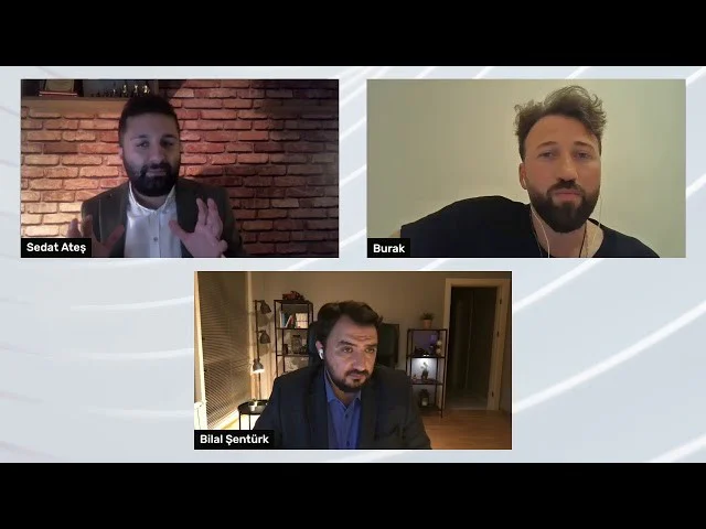 Görselde takım elbise giyen, sakallı ve bıyıklı bir adamın kolajı yer almaktadır. Adamın kulağında siyah kulaklıklar ve yüzünde kararlı bir ifade var. Sakalı ve bıyığı düzgünce kesilmiş olan adamın üzerinde ceketinin düğmeleri açık koyu gri bir takım elbise var. Kollarını göğsünün önünde kavuşturmuştur. Belden yukarısı üç çeyrek görünümde gösterilmiştir. Sağında, aynı sakal ve bıyığa sahip adamın yüzünün daha küçük bir görüntüsü yer alıyor.