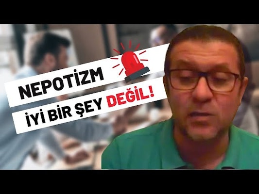 Parlak yeşil gömlek giyen bir adam beyaz bir arka planın önünde duruyor. Kısa siyah saçlı, gözlüklü ve yüzünde ciddi bir ifade var. Yüzüne yakından bakıldığında ciddi ifadesi ortaya çıkarken, arkasında siyah metinli ve kırmızı beyaz zeminli bir tabela görülüyor. Arka planda beyaz bir yüzey üzerinde kırmızı bir ışık da var. Adam hafifçe bulanıktır, bu da hareket halinde olduğunu göstermektedir. Gömleği, arka plandan sıyrılan canlı yeşil rengiyle görüntüdeki en görünür öğe.