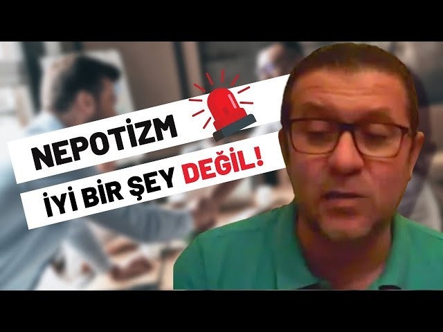 Parlak yeşil gömlek giyen bir adam beyaz bir arka planın önünde duruyor. Kısa siyah saçlı, gözlüklü ve yüzünde ciddi bir ifade var. Yüzüne yakından bakıldığında ciddi ifadesi ortaya çıkarken, arkasında siyah metinli ve kırmızı beyaz zeminli bir tabela görülüyor. Arka planda beyaz bir yüzey üzerinde kırmızı bir ışık da var. Adam hafifçe bulanıktır, bu da hareket halinde olduğunu göstermektedir. Gömleği, arka plandan sıyrılan canlı yeşil rengiyle görüntüdeki en görünür öğe.