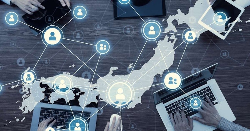 Bir grup insan önlerinde dizüstü bilgisayarları ve diğer cihazlarıyla bir masanın etrafında oturuyor. Bir kişi dizüstü bilgisayar klavyesinde yazarken, bir diğeri fare kullanmaktadır. Ön planda dizüstü bilgisayarda yazı yazan bir el ve arka planda üzerinde kişi simgesi olan bir büyüteç görülüyor. Ortadaki beyaz daire iki kişi içeriyor ve sağdaki başka bir beyaz dairede tek bir kişi var. Görüntü aynı zamanda beyaz bir çizginin yakın çekimini ve bir elin yakın çekimini de içeriyor. Odadaki herkes işine odaklanmış, bir şeyler yaratmak için birlikte çalışıyor.