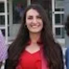 Genç bir kadın başını hafifçe yana eğmiş kameraya gülümsüyor. Uzun, siyah saçları zahmetsiz bir tarzda geriye doğru toplanmış. Gözleri keyifle parlıyor ve yanakları hafifçe pembe bir tonla kızarmış. Kısa kollu ve derin v yakalı beyaz bir tişört giyiyor. Dudakları sevincini ve memnuniyetini ifade eden hoş bir gülümsemeyle kıvrılmış. Duruşu rahat ve kaygısız ve sanki anın tadını çıkarıyor gibi görünüyor. Işık yüzünü aydınlatıyor ve doğal güzelliğini ortaya çıkarıyor. Kendine güvenin ve neşenin resmidir ve gülümsemesi gerçekten bulaşıcıdır.