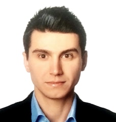 Resimdeki adam gri bir takım elbise giyiyor ve altında beyaz bir gömlek var. Düzgün, kısa siyah saçları ve temiz traşlı bir yüzü var. Parke zeminli, beyaz duvarlı ve arkasında pencere olan bir odada duruyor. Kendinden emin görünüyor, bakışları doğrudan ve duruşu dik. Elleri önünde kenetlenmiş ve sol bileğinde bir saat takılı. Kırklı yaşlarının ortasında ve profesyonelce giyinmiş görünüyor. İyi giyimli bir iş adamının mükemmel bir örneği.