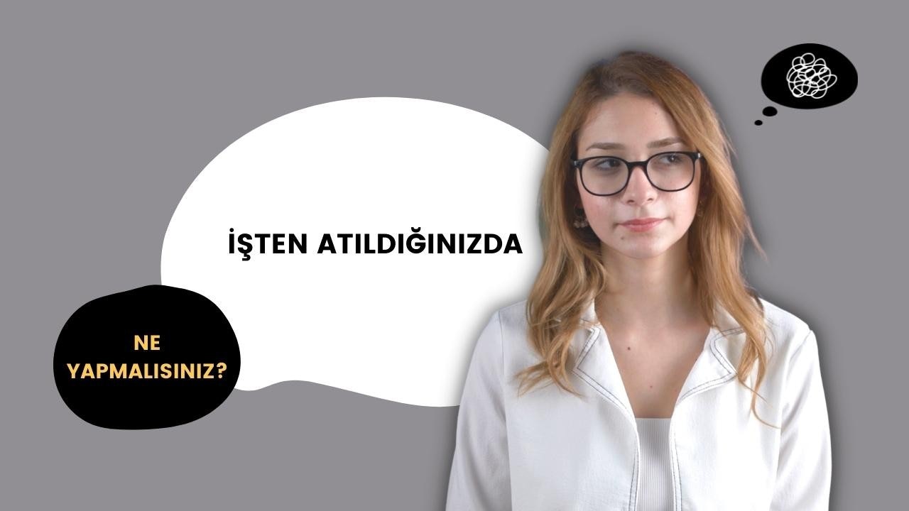 Gözlüklü ve beyaz ceketli bir kadın siyah ve sarı bir tabelanın önünde duruyor. Yüzünde ciddi bir ifadeyle dosdoğru ileriye bakıyor. Beyaz ceketinin düğmeleri iliklidir ve gözlükleri burnunun üzerine oturmaktadır. Saçları düzgün bir topuz yapılmış ve gözleri koyu renk eyeliner ile vurgulanmış. Ceketinin altına beyaz bir gömlek giymiş ve gömleğinin kumaşı boğazından ve göğsünden görünüyor. Arka plan bulanık ve renk paleti sessiz. Ellerini önünde kavuşturmuş, kendinden emin ve güçlü bir pozda duruyor.