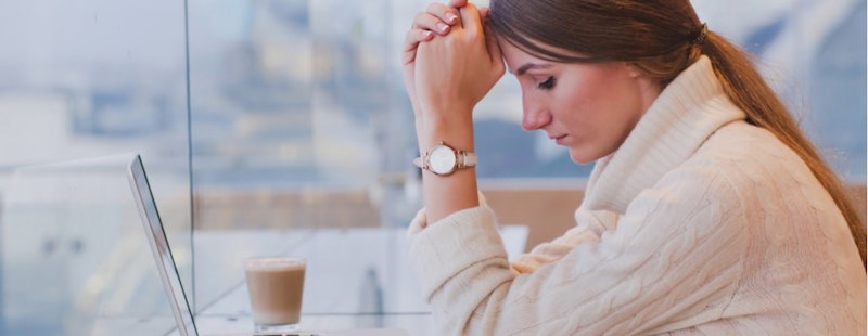 Resimde beyaz kazak giymiş, elleri başının üzerinde bir kadın görülüyor. Gözleri kapalı ve hafif sıkıntılı görünüyor. Kahverengi saçları hafifçe dağılmış ve dudakları birbirine bastırılmış. Arka planda, çoğunlukla dolu görünen bir bardak süt var. Bardak daireseldir ve üzerinde beyaz bir kapak vardır. Sahne çoğunlukla sol taraftan gelen doğal ışıkla aydınlatılmıştır. Kadın içerideymiş gibi görünüyor. Yüz ifadesinden bunalmış ve kararsız hissettiği anlaşılıyor.