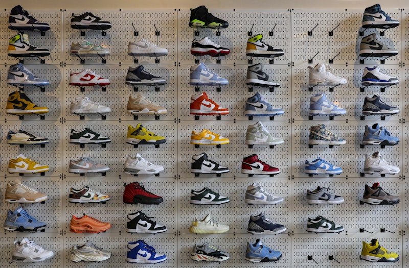 Bu görüntü, çok sayıda ayakkabıyla dolu bir duvarı tasvir ediyor. Duvar, mavi ve beyazdan kırmızı ve siyaha kadar değişen farklı renklerde ayakkabılarla kaplı. Ön planda sarı ve siyah bir ayakkabının yanı sıra kahverengi ve beyaz bir ayakkabı da görülebiliyor. Arka planda mavi ve siyah bir ayakkabının yakın çekimi görülüyor. Sarı etiketli bir ayakkabının yakın çekimi de resme dahil edilmiştir. Her ayakkabının kendine özgü bir tasarımı ve deseni vardır, bu da duvarın çok renkli ve canlı görünmesini sağlar.