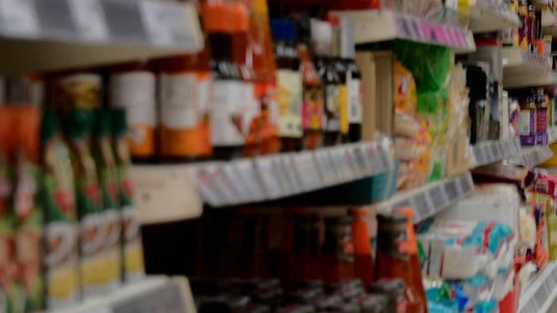 Bu, çeşitli ürün ve eşyalarla dolu bir mağaza rafının bulanık bir görüntüsüdür. Raf oldukça büyük ve birçok sıra düzgünce düzenlenmiş ürünle dolu. Ön planda, yüzeyine birkaç eşya yerleştirilmiş bir sandalye var. Rafta birkaç şişe var, hepsi biraz bulanık ve arka planda bir kişi var, yüzü de bulanık. Daha uzakta birkaç eşya daha var, ancak bunlar seçilemeyecek kadar bulanık. Resimdeki ışık oldukça loş, bu da resme hafif puslu bir görünüm veriyor. Sonuç olarak bu, arka planda bir kişinin olduğu, bazıları bulanık olan eşyalarla dolu bir mağaza rafının resmidir.