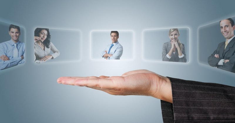 İnsanların resmini tutan bir elin yakın çekimi. Ön plandaki adam gri bir takım elbise giymiş ve gözlük takmış, kollarını kavuşturmuş. Solunda gözlüklü bir kadın resmi çenesine doğru tutmaktadır. Onların arkasında ise kravatlı ve gözlüklü bir başka adam kollarını kavuşturmuş. Resmin alt yarısında, arka planda koyu renkli bir kumaş görülüyor. Odak el ve resim üzerindedir, insanların detayları hafifçe bulanıktır. El, kararlılık duygusuyla resmi sıkıca kavrıyor.