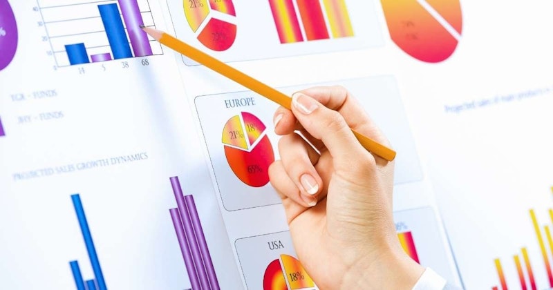 Bir kalemi kavrayan bir elin yakın çekimi. Kişi kalemi belli bir açıyla tutmaktadır ve kalemin üst kısmı aşağıya dönüktür. El bir grafiğin üzerine yerleştirilmiş ve kalem grafiğin kağıdına değiyor. Kalemin ucunda beyaz bir silgi kapağı vardır ve kişinin kolunda bir saat takılıdır. Kişinin cilt tonu açık ve tırnakları kesilmiş. Arka plan açık gridir.