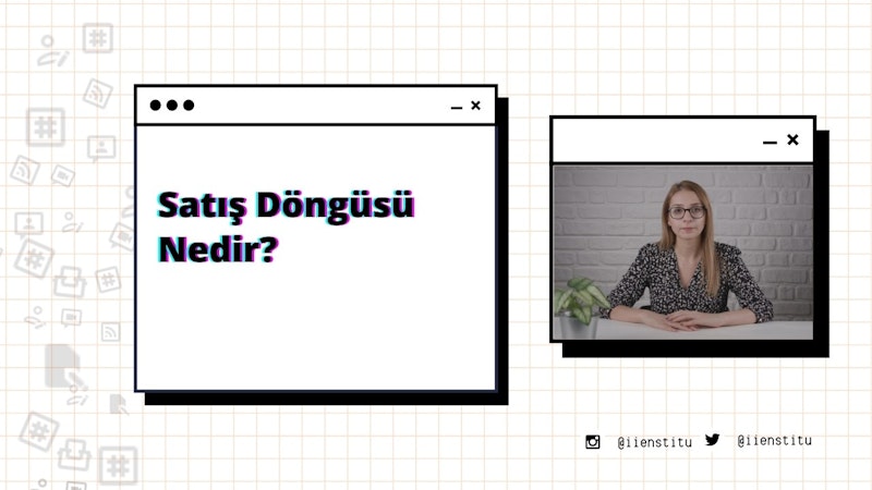 Bir kadın modern bir ofiste masasında oturuyor. Kollarını kavuşturmuş ve dümdüz ileriye bakıyor. Uzun, koyu renk saçları var ve siyah-mor bir gömlek giyiyor. Masanın üzerinde bir bilgisayar ve arka planda bir cep telefonunun ekran görüntüsü var. Sağında, her ikisi de hafifçe odak dışında kalan bir sebze ve bir bitki var. Solunda, üzerinde siyah ve kırmızı çizgiler olan beyaz bir kare ve bir bitkinin bulanık bir görüntüsü var.
