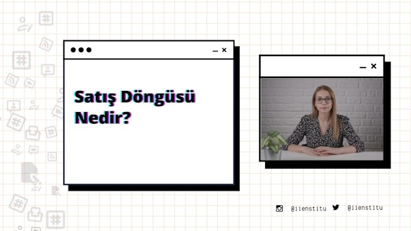 Bir kadın modern bir ofiste masasında oturuyor. Kollarını kavuşturmuş ve dümdüz ileriye bakıyor. Uzun, koyu renk saçları var ve siyah-mor bir gömlek giyiyor. Masanın üzerinde bir bilgisayar ve arka planda bir cep telefonunun ekran görüntüsü var. Sağında, her ikisi de hafifçe odak dışında kalan bir sebze ve bir bitki var. Solunda, üzerinde siyah ve kırmızı çizgiler olan beyaz bir kare ve bir bitkinin bulanık bir görüntüsü var.
