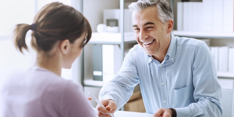 Biri erkek biri kadın iki kişi birbirlerine yakın durmakta, birbirlerine bakmakta ve gülümsemektedirler. Adamın üzerinde mavi düğmeli bir gömlek var ve elleri önündeki masanın üzerinde. Kadın saçlarını at kuyruğu yapmış ve beyaz bir gömlek giymiş. Adam sağ elinde bir kalem tutmaktadır. Görüntünün odağı gülümseyen yüzleri ve adamın gömleğinin yakın çekimidir. Mutlu ve rahat bir an yaşıyor gibi görünüyorlar. Görüntünün renkleri parlak ve neşeli. Arka plan bulanık ve ışık doğal.