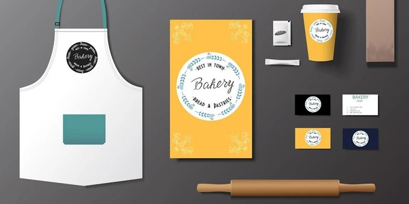 Bu resim bir masa üzerindeki bir grup eşyayı göstermektedir. Mavi ve beyaz metinli sarı ve beyaz bir etiket, beyaz kapaklı sarı bir fincan, mavi etiketli beyaz bir önlük, mavi ve beyaz metinli beyaz bir daire, beyaz metinli siyah bir daire, kahverengi dikdörtgen bir nesne, mavi ve beyaz bir ekran, siyah metinli beyaz bir daire ve beyaz metinli beyaz bir önlük ve sarı bir çanta bulunmaktadır. Etiket net bir dikdörtgen şekle sahiptir ve sarı zemin üzerinde mavi ve beyaz renklerde birkaç kelime içermektedir. Fincan silindiriktir ve beyaz bir kapağı vardır. Önlük beyazdır ve ön tarafında mavi bir etiket vardır. Beyaz dairenin üzerinde mavi ve beyaz yazılar vardır. Siyah dairenin üzerinde beyaz yazı vardır. Kahverengi dikdörtgen nesne pürüzsüz bir şekle sahiptir ve masanın alt kısmında yer alır. Mavi ve beyaz ekran dikdörtgen şeklindedir ve üzerinde birkaç düğme vardır. Beyaz dairenin üzerinde siyah yazı vardır. Beyaz önlük ve sarı çantanın üzerinde beyaz yazılar var.