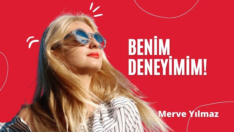 Güneş gözlüğü takmış bir kadın yukarı bakıyor. Parlak kırmızı bir arka planı var ve bu arka plan üstte keskin beyaz bir çizgiyle vurgulanıyor. Güneş gözlükleri benzersiz siyah çerçeveli bir stile sahip ve yüz ifadesi düşünceli. Beyaz bir tişört giyiyor ve tişörte yakından bakıldığında küçük mavi ve yeşil dairelerden oluşan bir desen görülüyor. Koyu renk saçlarını geriye doğru at kuyruğu yapmış ve güneş ışığı güneş gözlüklerinin camlarından yansıyor. Resmin sol alt köşesinde beyaz metinli büyük kırmızı bir işaret, sağ alt köşesinde ise beyaz metinli kırmızı bir kare yer alıyor. Görüntü bir beklenti ve merak hissi uyandırıyor.