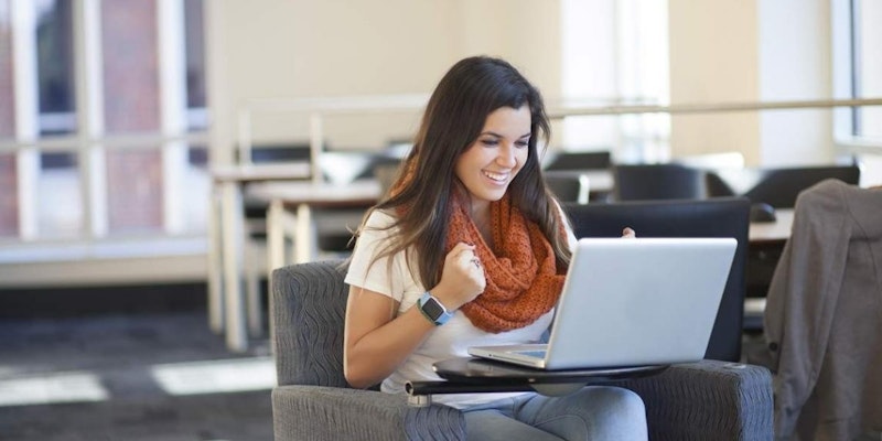 Genç bir kadın bir sandalyede oturmuş, dizüstü bilgisayarına bakıyor. Başında bir eşarp ve saat var; uzun, düz saçları var. Yüz ifadesi konsantre olmuş gibidir. Dizüstü bilgisayar açık ve ekran görülebiliyor. Yüzü kısmen kadraja girecek kadar ona yakındır. Dizüstü bilgisayar beyazdır. Sandalye nötr bir renktedir ve kadının giysileri çoğunlukla siyahtır. Oda iyi aydınlatılmış ve nötr renktedir. Kadının elleri dizüstü bilgisayarın üzerinde durmaktadır. Derin düşüncelere dalmış, dizüstü bilgisayarının içindekileri inceliyor gibi görünüyor.