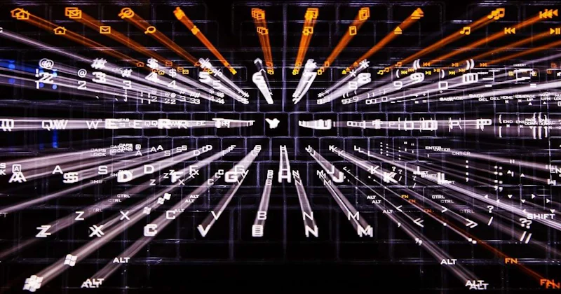 Bir bilgisayar klavyesinin bu yakın çekim görüntüsünde, üzerinde siyah yazılar ve rakamlar bulunan çok sayıda beyaz tuş görülüyor. Tuşlar dört sıra halinde düzenlenmiş gibi görünmektedir; üst sıra çoğunlukla rakamları, alt sıra ise harf tuşlarını içermektedir. Ayrıca görüntünün sağ alt kısmında birkaç ok tuşu ve sol üst kısmında bir kalem bulunmaktadır. Görüntü biraz bulanık olduğundan harf ve rakamların tüm detaylarını seçmek zorlaşıyor. Klavye parlak bir ışıkla aydınlatılarak görüntünün odak noktası haline getirilmiş.