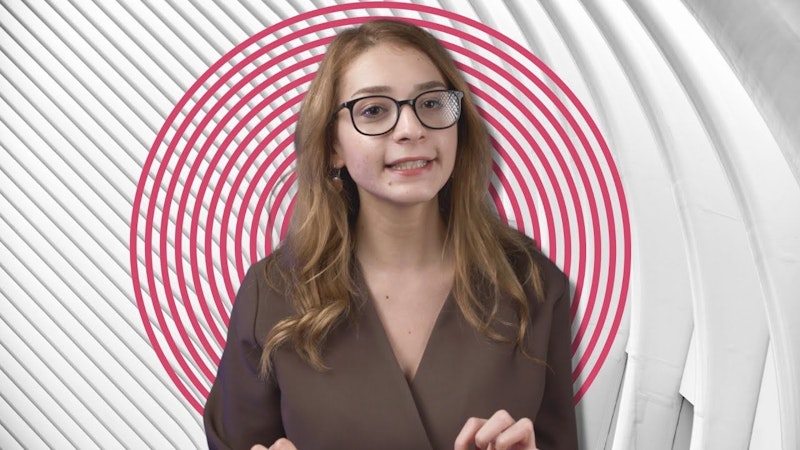 Bu resim gözlüklü ve kahverengi gömlekli bir kadını tasvir ediyor. Saçlarını toplamış ve gözleri dümdüz karşıya bakıyor. Gözlükleri biraz dikdörtgen çerçevelidir ve gömleği düz kahverengi renktedir. Sağ kolunda bir saat takılıdır. Ağzı hafifçe açık ve dudakları hafifçe büzülmüş. Kaşları hafifçe kalkık görünüyor. Elleri görüntüde görünmüyor. Sol kulağında tek bir halka küpe var. Arkasında beyaz bir duvar ve ahşap zemin bulunan iyi aydınlatılmış bir odada duruyor gibi görünüyor. Arka plan odak dışı, bu da fotoğrafçının kadına odaklandığını gösteriyor.