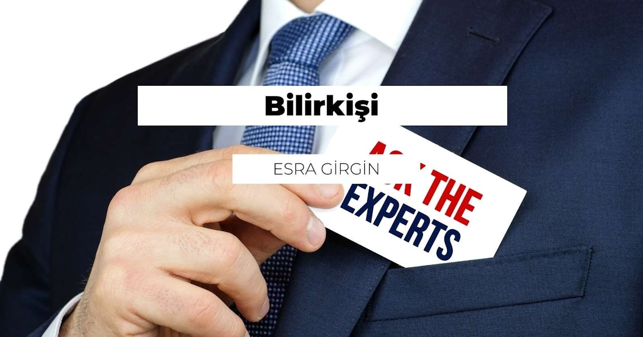 Bir takım elbisenin cebine bir kart yerleştiren bir kişinin elinin yakın çekimi gösterilir. Kart beyazdır ve üzerinde siyah beyaz bir logo basılıdır ve kişinin parmağı görünmektedir. Takım elbise siyahtır ve kravat da yakın plandadır, üzerinde bir desen vardır. Cep hafifçe açık ve kişi kartı parmağıyla içeri itiyor. Cep derindir ve kart neredeyse tamamen içeride gizlenmiştir. Kişi görevi tamamlamaya niyetlidir ve görüntünün odak noktası elidir. Işık doğal ve görüntü net ve odaklanmış.