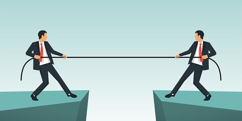 Bu resimde takım elbiseli iki adam, her iki taraftan birer ip çekerken görülüyor. Soldaki adamın üzerinde koyu lacivert bir takım elbise, altında beyaz bir gömlek ve lacivert bir kravat var. Kısa siyah saçları var ve kameradan uzağa bakıyor. Sağdaki adam açık gri bir takım elbise, beyaz bir gömlek ve çizgili kırmızı beyaz bir kravat giyiyor. Kısa, açık kahverengi saçları var ve doğrudan kameraya bakıyor. Her iki adam da beyaz bir zemin üzerinde durmakta ve halatı çekerken kollarını uzatmaktadır. Halat açık kahverengi renktedir ve iki adam arasında gergindir. Görüntü, parlak renkleri ve mizah duygusuyla karikatür benzeri bir havaya sahiptir.