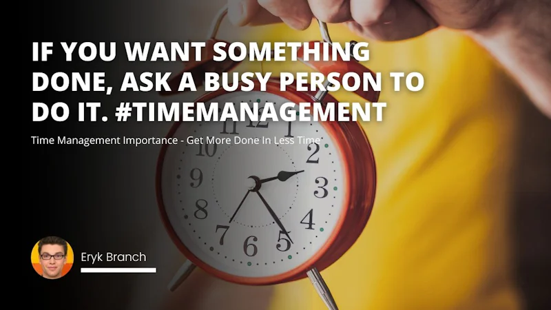 A person is holding a clock up to their face, wearing glasses. The clock has text etched into it, and the hand of the person holding the clock is visible. The clock is a bright red color, and the person is focusing intently on the timepiece. The person's face is obscured by the clock, but the detail of the clock is clear. The clock is held close to the person, so that only the hand and the clock is visible.