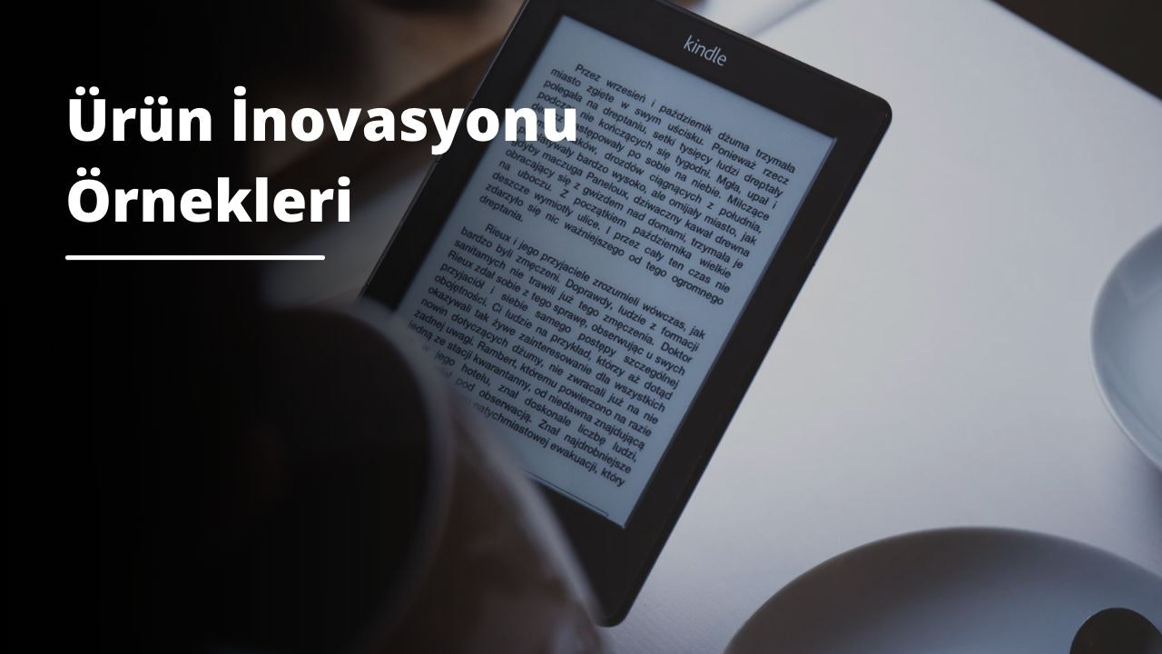 Resimde bir tabletin yakın çekimi gösterilmektedir. Cihaz beyazdır ve sağ köşesinde siyah bir tutma yeri vardır. Sol tarafta ekran görünmekte ve tablet dikdörtgen şeklinde görünmektedir. Arka plan açık gri renktedir. Sağ tarafta kulplu siyah bir kase var ve oldukça büyük görünüyor. Kasenin sol tarafında bir kitap görülüyor. Koyu yeşil bir kapağı ve ön yüzünde beyaz bir yazı vardır. Sayfalar hafifçe kıvrılmış ve oldukça kalın görünüyor.