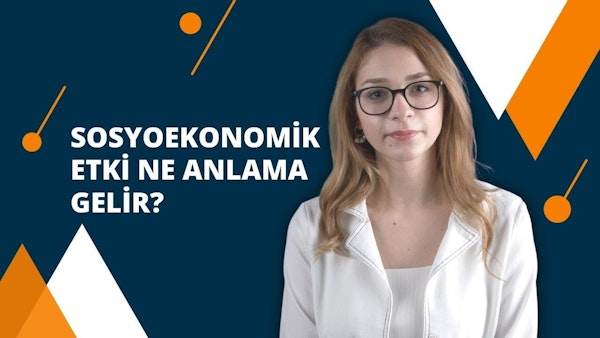 Bir kadın beyaz bir gömlek ve gözlük takıyor. Uzun, koyu kahverengi saçları var ve gözleri gözlüklerin arkasından görünüyor. Gözlük ince, siyah bir çerçeveye sahip ve camları hafifçe renklendirilmiş. Beyaz gömleğin sol tarafında küçük turuncu bir daire var. Kadın doğrudan kameraya bakıyor, ifadesi odaklanmış ve niyetli. Arka plan koyu, parlak bir mavidir ve sol üst köşede beyaz bir metin yazılıdır. Görüntü kadının yüzünün ve göğsünün yakın çekimidir, gözleri ve gömleği çerçevenin büyük kısmını kaplamaktadır. Işık yumuşaktır ve kadının yüz hatlarını vurgulayarak görüntüye doğal ve davetkar bir görünüm kazandırır.