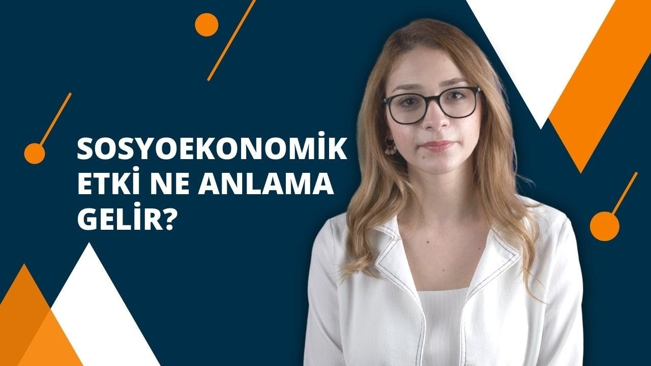 Bir kadın beyaz bir gömlek ve gözlük takıyor. Uzun, koyu kahverengi saçları var ve gözleri gözlüklerin arkasından görünüyor. Gözlük ince, siyah bir çerçeveye sahip ve camları hafifçe renklendirilmiş. Beyaz gömleğin sol tarafında küçük turuncu bir daire var. Kadın doğrudan kameraya bakıyor, ifadesi odaklanmış ve niyetli. Arka plan koyu, parlak bir mavidir ve sol üst köşede beyaz bir metin yazılıdır. Görüntü kadının yüzünün ve göğsünün yakın çekimidir, gözleri ve gömleği çerçevenin büyük kısmını kaplamaktadır. Işık yumuşaktır ve kadının yüz hatlarını vurgulayarak görüntüye doğal ve davetkar bir görünüm kazandırır.