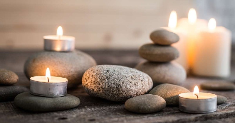 Görüntüde bir grup kaya ve yanan mumlar görülüyor. Kayalar üst üste yığılmış ve bir kayanın yakın çekimi ön planda görülebiliyor. Arka planda da siyah bir nesne görülüyor. Mumlar kayaların arasına yerleştirilmiş, sol alt köşede bir yakın çekim mum ve sağ üst köşede bir başka yakın çekim mum görülüyor. Mumlar yanmakta olup sıcak ve davetkâr bir atmosfer sağlamaktadır. Resmin sağ alt köşesinde de bir kaya yığını ve mumlar var. Huzur ve dinginlik hissi veren bu görüntü, herhangi bir görüntü başlığı veri kümesine harika bir katkı sağlayacaktır.