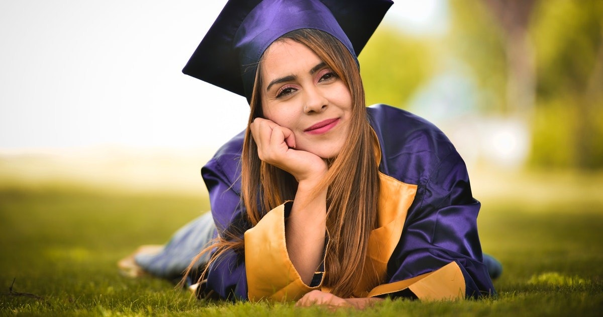 Mezuniyet cübbesi giymiş bir kadın çimlerin üzerinde yüzüstü yatıyor. Ellerini yüzüne koymuş, burnu ve gözleri yakın çekimle görülebiliyor. Mezuniyet kepi gibi kolu da yakın çekimde görülebiliyor. Üzerinde siyah kuşaklı beyaz bir cüppe var ve gözleri kapalı. Huzurlu bir pozda, görünüşe göre etrafındaki güneş ışığının tadını çıkarıyor.