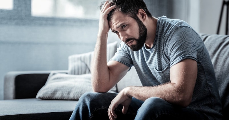 Siyah gömlekli bir adam beyaz bir kanepede oturmuş, elini alnına dayamış. Kalın, koyu renk bir sakalı vardır ve yüzünde dalgın bir ifadeyle aşağıya doğru bakmaktadır. Gözleri kapalı ve kaşları çatık, derin düşüncelere dalmış izlenimi veriyor. Görüntü arka planda hafifçe bulanıklaşmış ve köşede beyaz bir yastık görülüyor. Adam kendi dünyasında kaybolmuş, derin düşünce ve tefekkür içinde görünüyor.