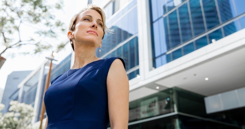 Bu görüntü parlak mavi elbiseli bir kadını tasvir ediyor. Kadın arka plandaki bulanık bir bina görüntüsünün önünde durmaktadır. Kadının başı hafifçe yukarı eğik ve yüz ifadesi nötr. Elbisesi dizlerinin hemen altına kadar uzanıyor ve v yakalı bir kesime sahip. Omuz hizasındaki saçları yüzünden uzakta geriye doğru toplanmıştır. Göğsünün yakın çekiminde küçük bir kolye ucu olan narin bir kolye görülüyor. Sol kolunu hafifçe kaldırmış ve sağ elini kalçasına dayamış. Resmin alt köşesinde bir ağacın bulanık görüntüsü görülebiliyor. Bu kadın rahat bir pozda duruyor ve mavi elbisesinin içinde kendinden emin görünüyor.