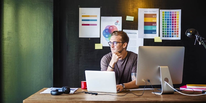 Açık renkli gömleği ve koyu renkli pantolonu olan bir adam bilgisayarın önünde bir masada oturuyor. Monitöre bakıyor ve elini çenesine dayamış, derin düşüncelere dalmış. Monitör yakın çekimdir ve yanında bir elin üzerinde durduğu bir dizüstü bilgisayar vardır. Masanın üzerinde duran beyaz dikdörtgen bir nesneye bağlı beyaz bir kablo vardır. Ayrıca sayılar ve semboller içeren bir çizelgenin yakın çekimi de vardır. Adam konsantre olmuş bir ifadeyle ekrana odaklanmıştır. Bilgisayardan gelen ışıkla aydınlanan adam sahneye sıcak ve davetkâr bir hava katıyor.