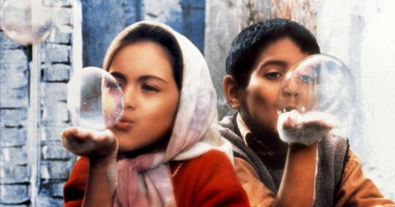 Resimde biri kız diğeri erkek iki çocuk baloncuk üflerken görülüyor. Kız çocuğu pembe bir bluz giyiyor ve uzun kahverengi saçları var. Yüzünde kararlı bir ifadeyle baloncuk üflüyor. Mavi bir tişört giyen erkek çocuk da heyecanlı bir ifadeyle baloncuk üflüyor. Arka planda, bulanık ve flu olmasına rağmen bir kişinin yüzünün yakın çekimi görülebiliyor. Görüntünün sağ alt köşesinde de bir kişinin karnının yakın çekimi görülüyor. Tüm çocuklar güzel bir gökyüzü ve yemyeşil ağaçlarla çevrili aydınlık bir açık hava ortamındadır. O anın neşesi hissediliyor ve görüntü çocukluğun masumiyetinin büyülü hissini yakalıyor.