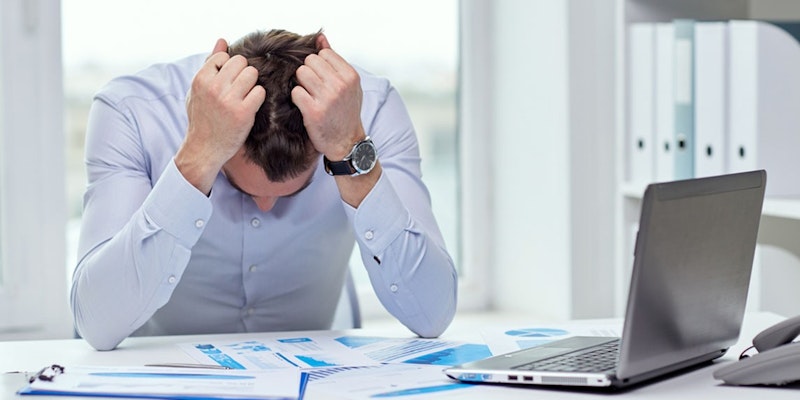 Yüzünde sıkıntılı bir ifadeyle başını ellerinin arasına almış bir adam görülüyor. Elleri alnının biraz üzerinde durmakta ve parmakları avuç içleri başının yanlarını kavrayacak şekilde kıvrılmış durumda. Kısa kahverengi saçları vardır ve beyaz bir tişört giymektedir. Arka planda bir dizüstü bilgisayar, bir saat, bir bilgisayar faresi, bir cilt, bir masanın üzerinde kağıtlar ve bir yığın kağıt var. Önündeki içeriği düşünürken derin düşüncelere dalmış gibi görünüyor. Görüntü, adam zor bir kararla mücadele ederken stres ve zorluk hissi uyandırıyor.