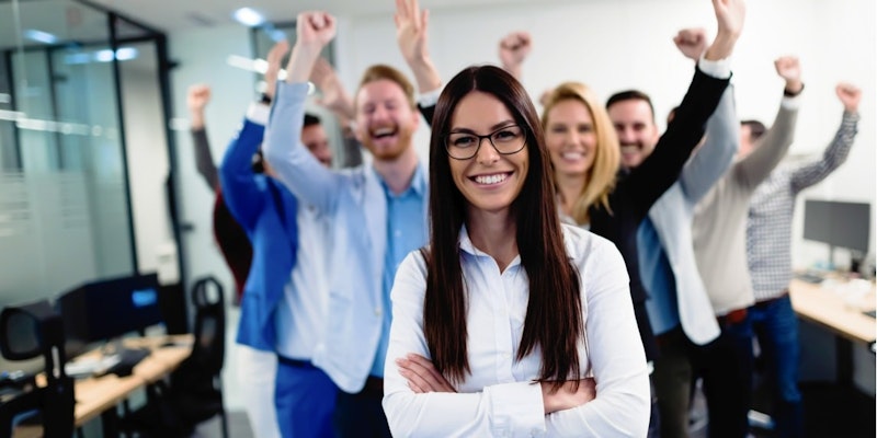 Bir grup insan başka bir grup insanın önünde durmakta ve ellerini havaya kaldırmaktadır. İlk grupta uzun saçlı, gözlüklü ve gülümseyen bir kadın var. Kollarını havaya kaldırmış bir adam da var. Arka planda ellerini kaldıran insanların bulanık bir görüntüsü ve bir gölgenin yakın çekimi var. Arka planda ayrıca kollarını kaldırmış bir grup insan görülüyor. Ayrıca bir televizyonun, siyah dikdörtgen bir nesnenin ve bir adamın yüzünün bulanık bir görüntüsü var. Son gruptaki insanlar kollarını kavuşturmuş.