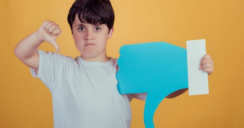 Genç bir çocuk mavi bir kâğıt parçasını başparmağını yukarı kaldırarak havada tutuyor. Beyaz bir gömlek giymiş ve yüzünde ciddi bir ifade var. Dudakları hafifçe büzülmüş ve gözleri kâğıda odaklanmıştır. Sağ kolu kameraya doğru uzatılmış, sol kolu ise dirseğinden bükülmüş ve kâğıdı tutmaktadır. Kâğıt mavidir ve sağ üst köşesinde beyaz bir başparmak yukarı sembolü vardır ve çocuk beyaz bir arka planın önünde durmaktadır. Kararlı ve gururlu görünüyor ve elinde tuttuğu kağıt değer verdiği bir şeyin sembolü.