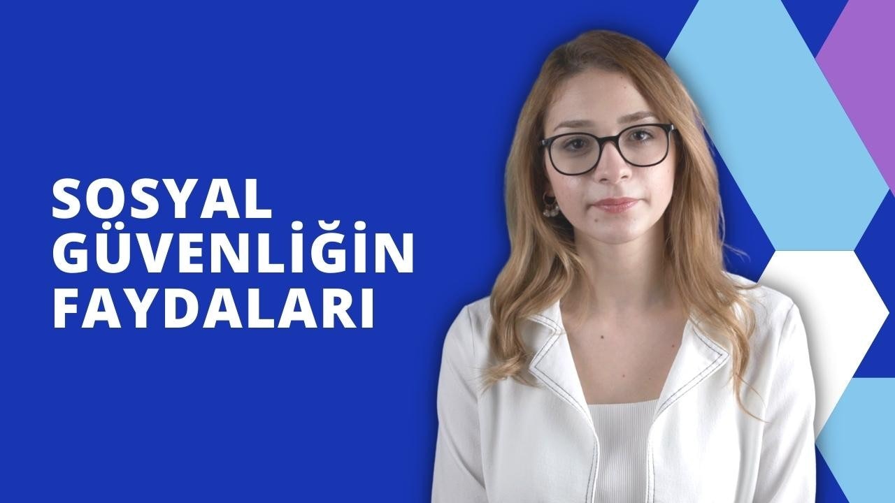 Beyaz ceketli ve gözlüklü bir kadın kameranın önünde durmaktadır. Gözleri kapalıdır ve gözlükleri ortamın ışığını yansıtmaktadır. Ceketinin geniş bir yakası vardır ve boynuna kadar düğmelidir. Saçları arkaya toplanmıştır ve yüzü gözlükleriyle çerçevelenmiştir. Ten rengi açık ve dudakları hafifçe ayrılmış. Parlak bir ışıkla aydınlatılmış açık bir alanda durmaktadır. Elleri ceplerinde ve duruşu rahat. Yirmili yaşlarının sonunda ya da otuzlu yaşlarının başında görünüyor. Yüz hatları belirgin ve ifadesi huzurlu.