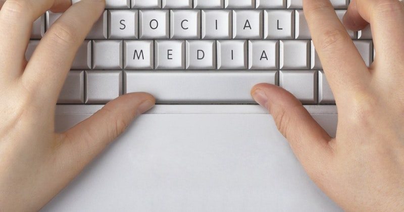 Beyaz tuşları olan siyah bir klavye üzerinde yazı yazan iki elin yakın çekimi. Sağ el işaret, orta ve yüzük parmaklarıyla üç tuşu basılı tutarken, sol el işaret ve orta parmaklarıyla iki tuşu basılı tutmaktadır. Her iki elin serçe parmakları herhangi bir tuşun üzerinde değildir. Klavye, siyah ve beyaz tuşlar arasındaki kontrastı artıran parlak bir ışıkla aydınlatılmıştır. Tuşlarda hafif bir parlaklık var ve bu da görüntüye genel olarak parlak bir görünüm veriyor. Görüntünün sol üst köşesinde ince bir ışık ipucu var.