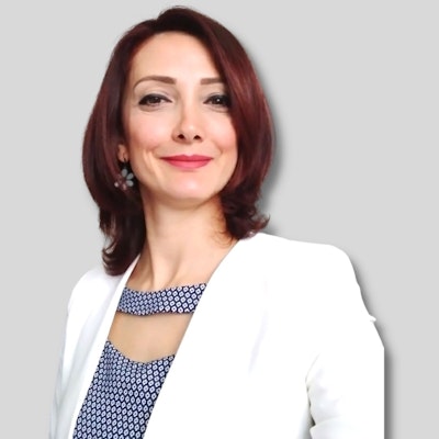 The photo shows a woman with a bright, warm smile, looking directly at the camera. Her eyes are bright and her lips are slightly parted, indicating her cheerful nature. She is wearing a white jacket, which is a classic garment for teachers. The photo is a close-up of her face and chest, with her eyes and nose clearly visible. Her facial features are composed and her hair is neatly styled, giving the impression of a competent and professional instructor. The photo also showcases her beauty and personality, suggesting she has the qualities of a great teacher. The photo gives a sense of confidence, respect, and friendliness, making it the perfect image to represent a course instructor.