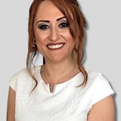 A young woman stands in front of a white wall, wearing a white t-shirt and blue jeans. Her hair is mid-length and blonde, and her eyes are a deep blue. She stands confidently, her eyes focused on something unseen. Her arms are at her sides, her hands clenched into fists. Her lips are slightly parted, her expression determined and strong. She stands in the light, her figure framed by shadows and highlighted by the white of her shirt. Her posture is relaxed, and her gaze is confident. She is a force to be reckoned with, her presence both confident and powerful.