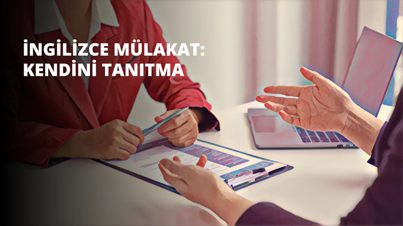 Bir kişi sağ elinde bir kalem tutmakta ve sol eliyle beyaz bir panoya işaret etmektedir. Kişi mavi bir gömlek giymektedir ve koyu renk saçları vardır. Sağ kolu uzatılmış ve sol kolu bükülmüş, işaret parmağı ve başparmağı panoya doğru uzatılmıştır. Arka planda bir dizüstü bilgisayar ve bir masada oturan başka insanlar var. Görüntü hafif bulanık ve köşede renkli bir nesne var.